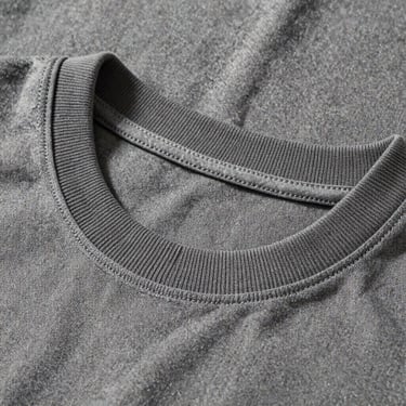 Clean macro shot of a ribbed collar of an organic cotton t-shirt, showcasing robust construction and double-stitched seams.