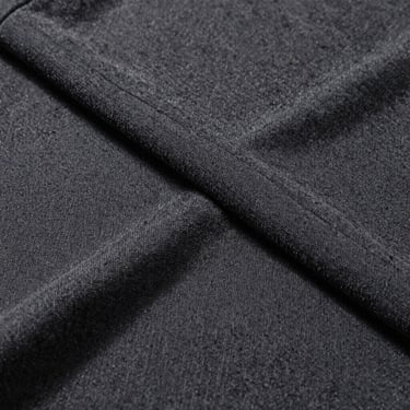 Macro texture of a heavy 240gsm organic cotton t-shirt in deep charcoal, showing the tightly woven premium knit, direct sunlight.
