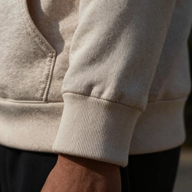Close-up of a premium brushed cotton hoodie sleeve cuff, showing the dense weave and clean stitching details, dramatic side light.