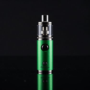 Premium anodized aluminum vape mod with glass tank, standing upright on reflective black glass, moody low-key studio lighting, neon green highlight, 50mm