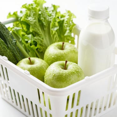 A close-up of a bright, clean grocery basket filled with fresh green vegetables, apples, and organic milk under natural daylight