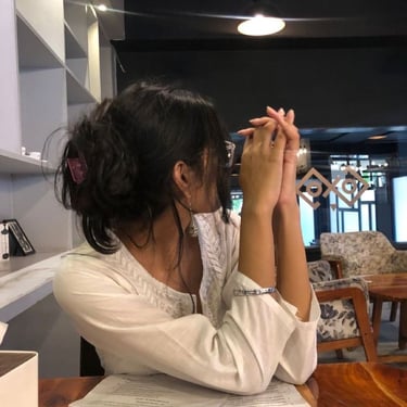 Here is your SEO-optimized alt text:  ALT TEXT: Woman in white embroidered top with messy bun