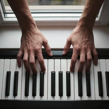 Overhead tight shot of hands pressing piano keys under a narrow north-facing window beam, fingers mid-motion, deep shadow framing the keys at the bottom edge