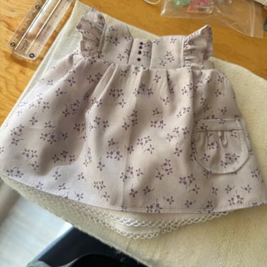 Vestido lila con flores para muñeca waldorf en el fondo una regla y material de costura