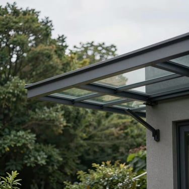 Low-angle architectural shot of a modern dark grey aluminum patio cover with integrated glass panels, attached to a minimalist house wall, overcast sky, 35mm