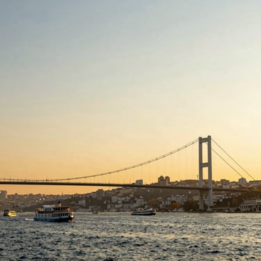 Bosphorus bridge in Istanbul, Turkey at golden hour, warm sun-drenched sky, boats on the water.