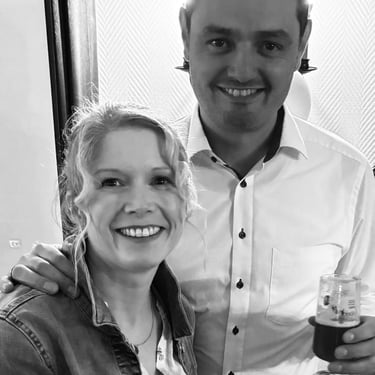 A smiling couple posing for a black and white portrait at a social event with drinks.