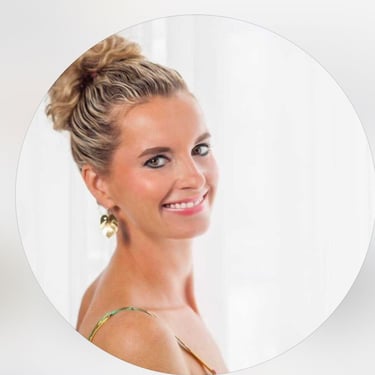Smiling woman with blonde curly hair in a bun wearing gold leaf earrings in a professional circular headshot.