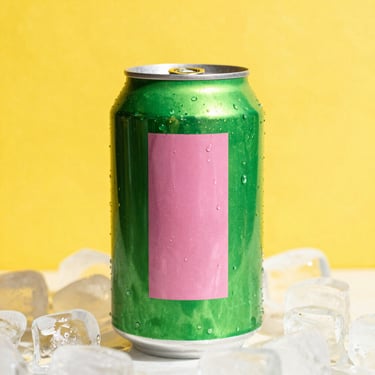 Vibrant pop-art close-up of a bright green and pink soda can on ice, set against a solid bright yellow background, direct harsh sunlight