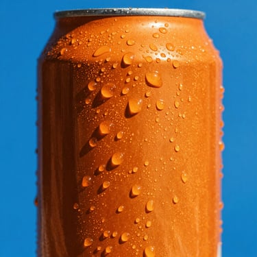 Vibrant pop-art close-up of a bright orange soda can with condensation drops, set against a solid electric blue background, direct harsh sunlight, sharp shadows