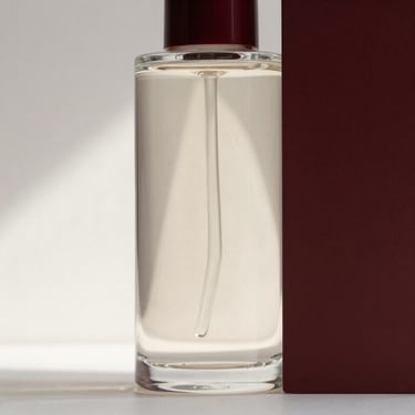 Minimalist composition of a sleek glass bottle reflecting soft architectural shadows, clean luxury aesthetic