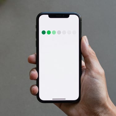 Hand holding an Android phone showing a minimal habit tracker — a row of seven small circles, two filled in green, on a white background, close-up, soft daylight, no background clutter