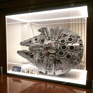 Le set LEGO Millennium Falcon (75192) exposé verticalement dans une vitrine rétroéclairée, accompagné de ses figurines.