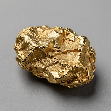 Overhead flat-lay macro of a high-purity gold specimen on a museum-gray surface, studio north light revealing crystalline grain structure and surface texture, minimal props, generous negative space