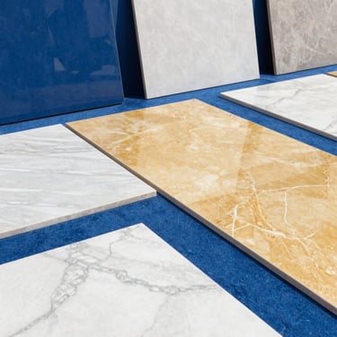 Polished marble slabs and premium architectural ceramic tiles arranged geometrically in a bright, high-key showroom