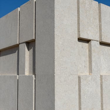 Macro photograph of dense concrete block texture, clean geometric edges, architectural gray, sharp daylight shadows
