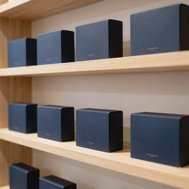 Clean packaged consumer goods on a minimalist wooden shelf, warm lighting, elegant B2B retail packaging