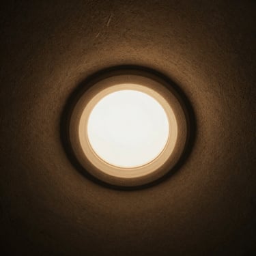 Close-up of a miniature plaster-in plaster-ring trimless downlight, seamless edge blending into a textured wall.