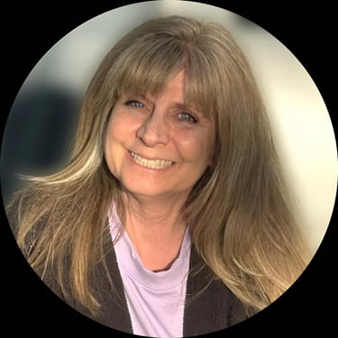 Headshot of a smiling woman with long blonde hair and bangs wearing a purple shirt.