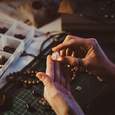Mujer haciendo collares artesanales con piedras preciosas