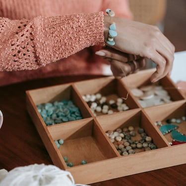 mujer creando una pulsera con piedras naturales 