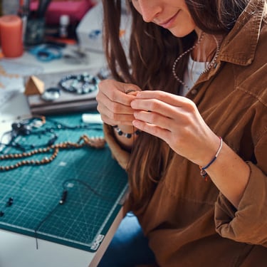 mujer sonriendo mientras elabora una pieza de joyería artesanal 