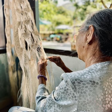 mujer mayor tejiendo adorno de macramé en un taller al aire libre