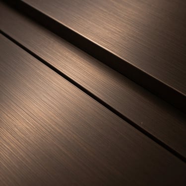 Abstract texture of brushed bronze and dark steel, sharp linear reflections, low-key natural light