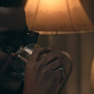 Close-up of a man drinking in warm lamp light in the short film Grief by Daniel da Trindade.