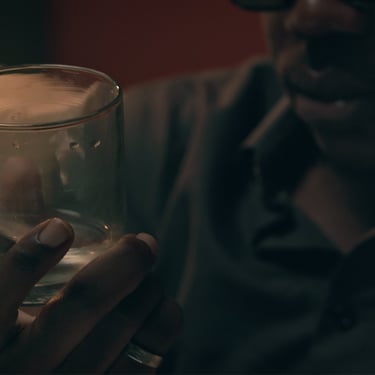 Character holding a glass in a reflective moment from the short film Grief by Daniel da Trindade.