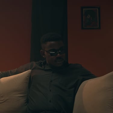 Wide cinematic frame from the short film Grief showing a man sitting in a dimly lit living room.