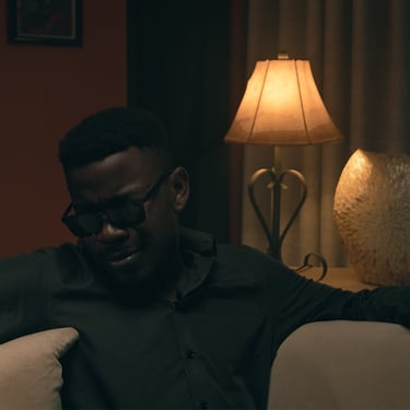 Cinematic wide shot of a man sitting on a couch in the short film Grief directed by Daniel da Trindade.