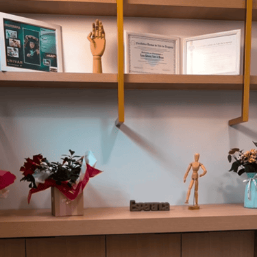 Prateleira com certificados, diplomas e quadros que comprovam a qualificação e formação da profissional da Clínica Lanna Mora