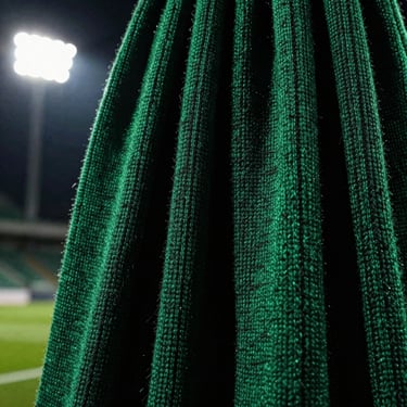 Close-up of heavyweight woven scarf texture, deep pitch-green and black threads, dramatic side lighting.