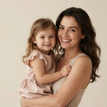 Portrait of a smiling mother holding her young daughter who is wearing a pale dusty rose dress, studio lighting, soft cream background.