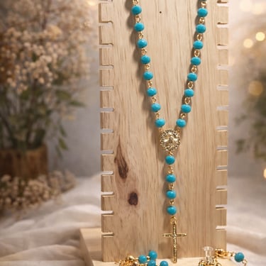 Set de rosario con pulsera y aretes color azul en un fondo de flores y madera