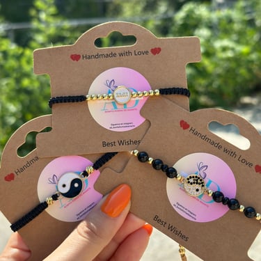 Tres diferentes pulseras tejidas a mano con fondo verde y sostenidas por una mano