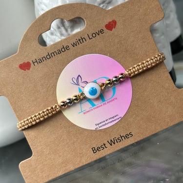 Pulsera tejida con detalles dorados y un ojo turco