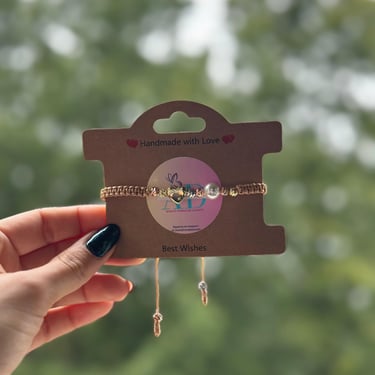 Pulsera hecha a mano con corazon y perlas blancas en un fondo natural