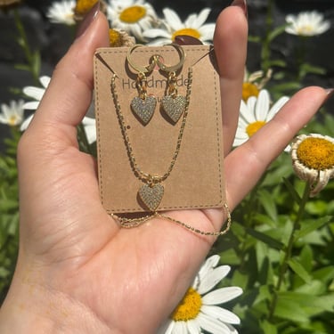 Set de aretes y collar corazones dorados en un fondo primaveral