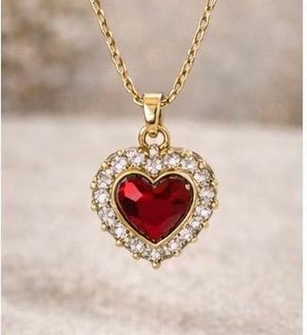 Collar corazon rojo con detalles dorados en un fondo suave