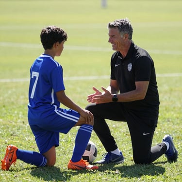 A coach kneeling to talk to a young soccer player on a sunny green field, encouraging smile, bright daylight