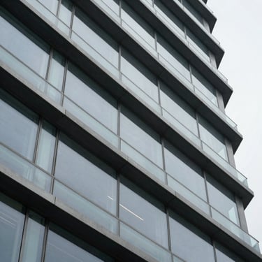 Macro close-up of a structured architectural facade with clean steel and glass lines under cool overcast daylight, sharp focus on geometric patterns
