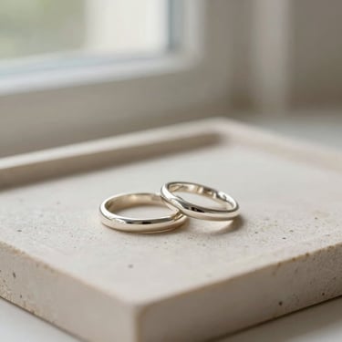 Elegant silver rings stacked on a light stone tray, soft natural lighting, shallow depth of field