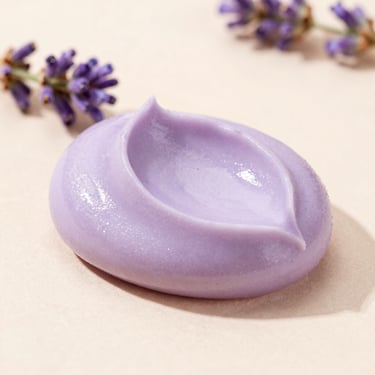 Close-up of a soft lavender-colored cream paleta with a tiny sprig of lavender beside it, soft daylight, pastel background