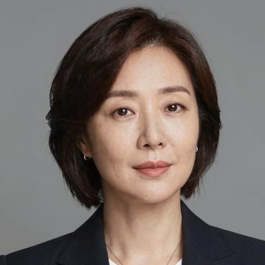 A man happily practicing English on his laptop in a bright, homey living room.