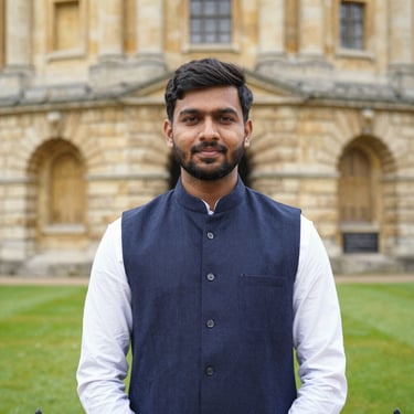 Indian male student standing near a scenic Canadian university entrance with books in hand