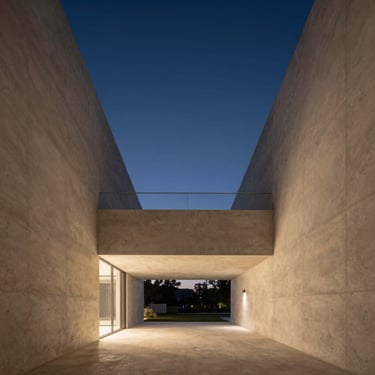 Minimalist luxury residential interior with concrete walls, high ceilings, and warm evening light, sharp architectural photography