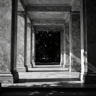 High-contrast black and white medium format architectural photograph of a modern marble pavilion, symmetrical columns, deep shadows.