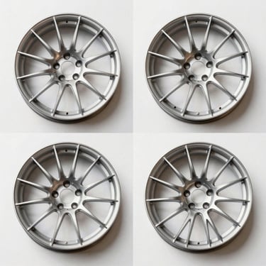 Overhead size-comparison studio grid of four forged aluminum wheels laid flat on a white ground, hard top-down strobe lighting, equidistant spacing revealing diameter and spoke profile differences between sizes, stark white background, no labels or graphics